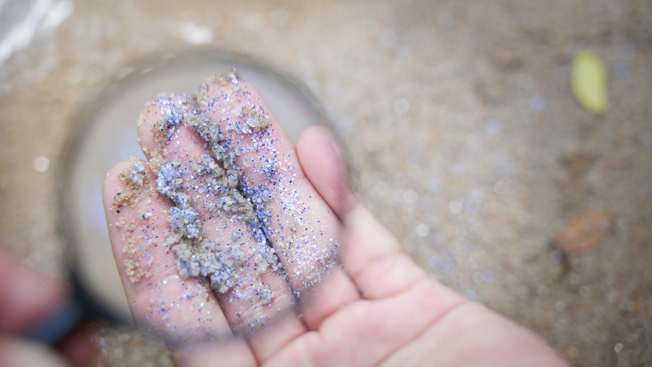 Mano con microplásticos recogidos de la playa